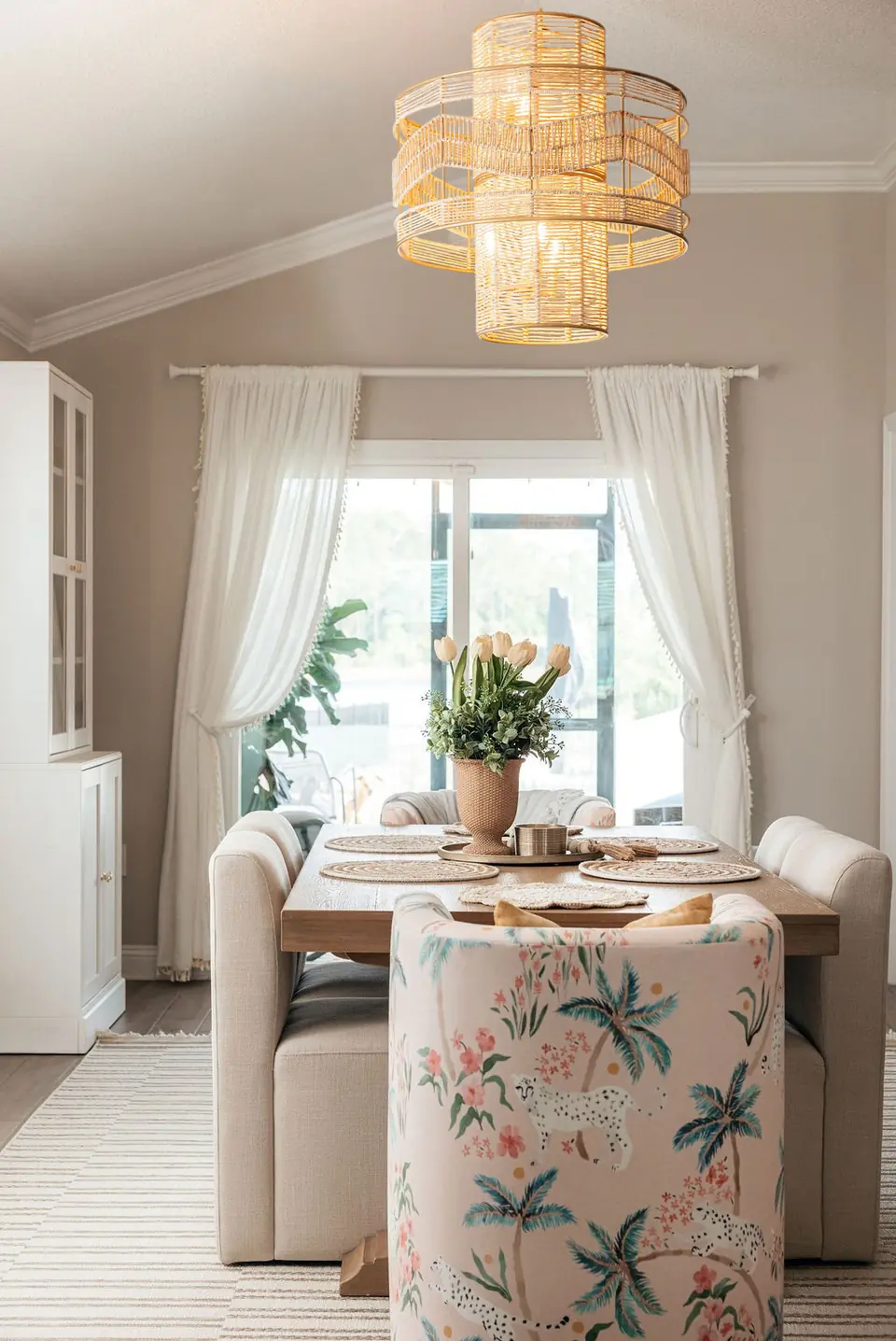 Dining room designed by Zen Reno & Design in St. Augustine, FL, featuring whimsical patterned dining chairs, a statement woven chandelier, custom furnishings, and soft color accents that bring character and personality to the space.