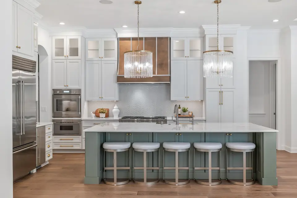 Luxury Kitchen designed by Zen Reno & Design in St. Augustine, FL, featuring statement crystal pendant lighting, a custom sage green island, warm brass accents, and tailored cabinetry for a distinctive and elevated look.