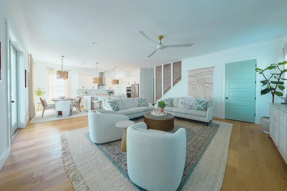 Open concept living room and kitchen designed by Zen Reno & Design featuring layered textures, subtle pattern, soft blue accents, and custom furnishings in St. Augustine, Florida.