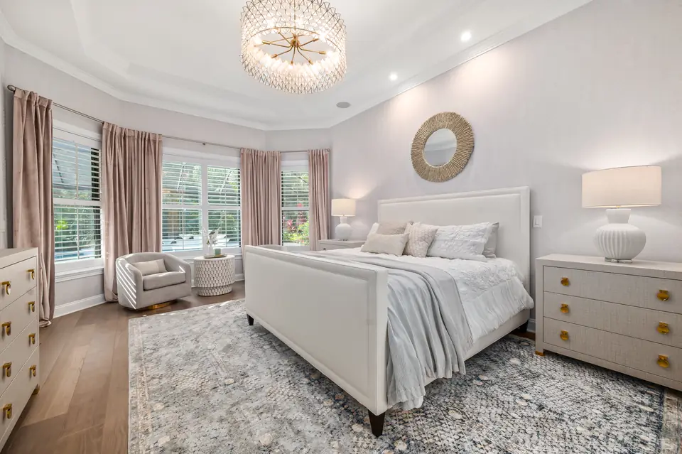Primary bedroom designed by Zen Reno & Design in St. Augustine, FL, featuring statement crystal lighting, patterned textiles, custom drapery, and tailored furnishings that create a refined and inviting retreat.